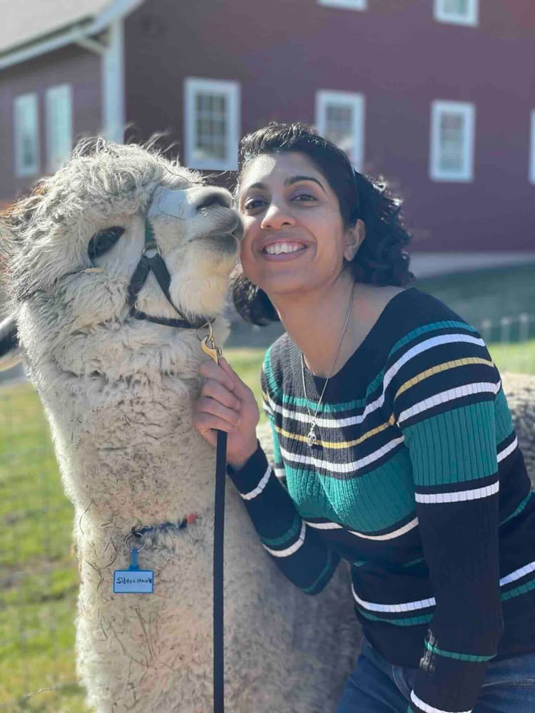 Dr. Modi posing with white alpaca outdoors