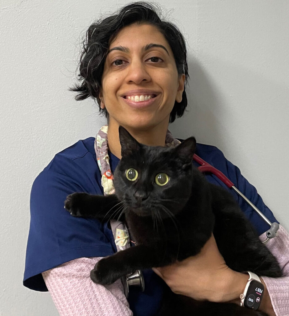 Dr. Modi in dark blue scrubs with her black cat, Faile.