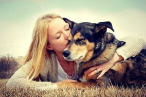 Woman tenderly embracing senior dog outdoors