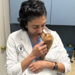 Dr. Modi in white coat gently holding tan puppy